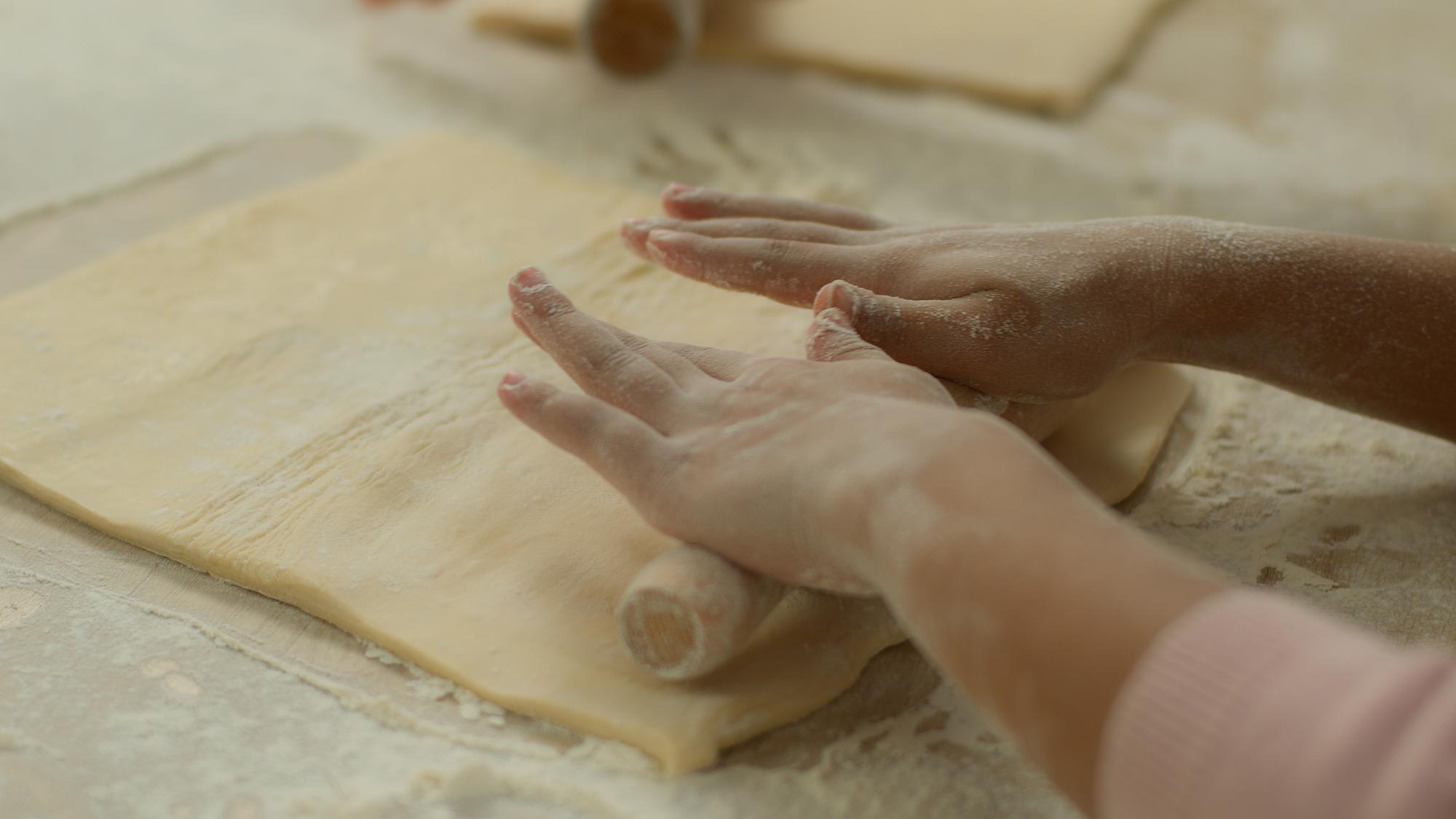 Dettaglio di mani che impastano su una superficie in legno